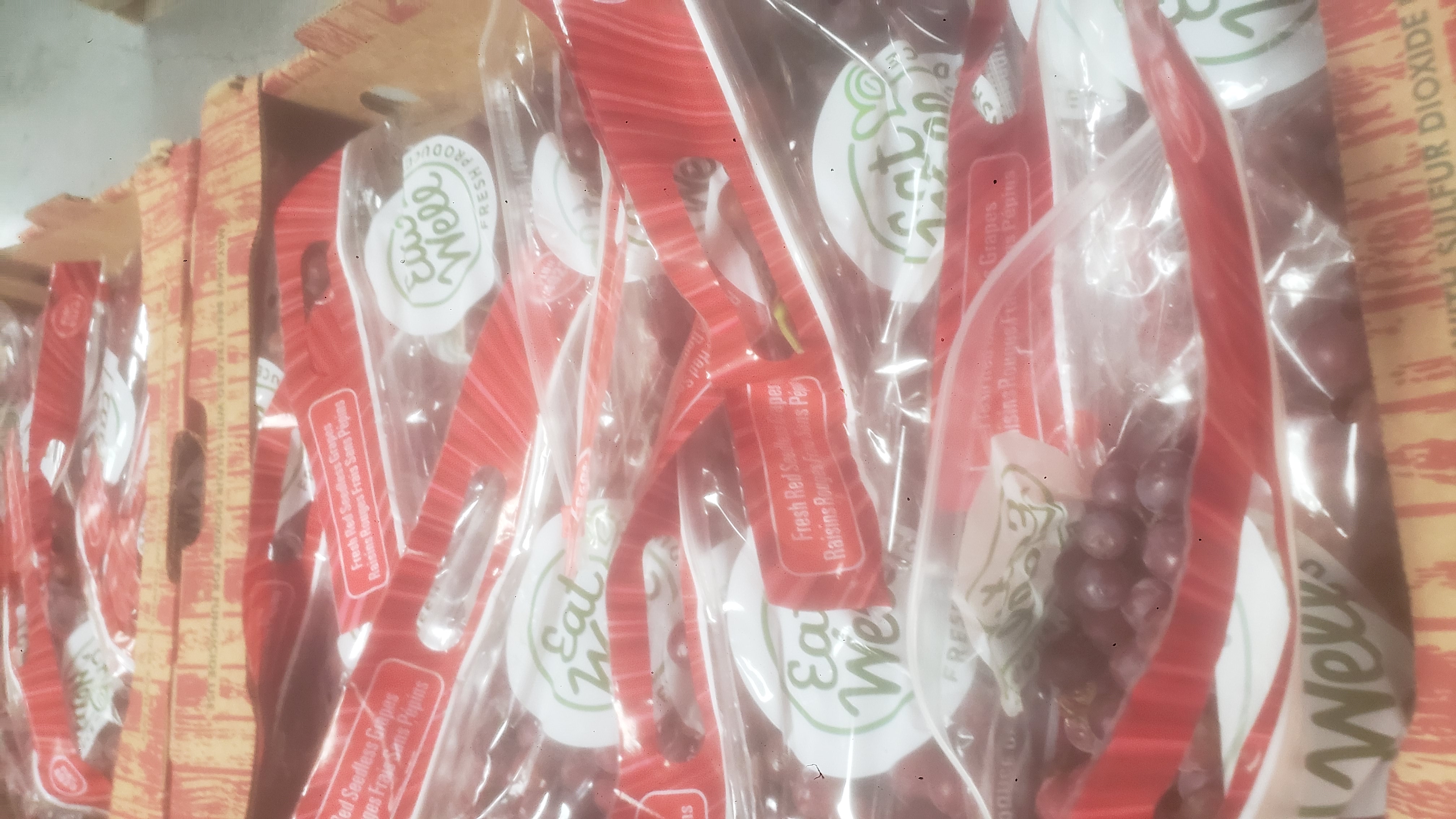 Bags of red grapes in trays.